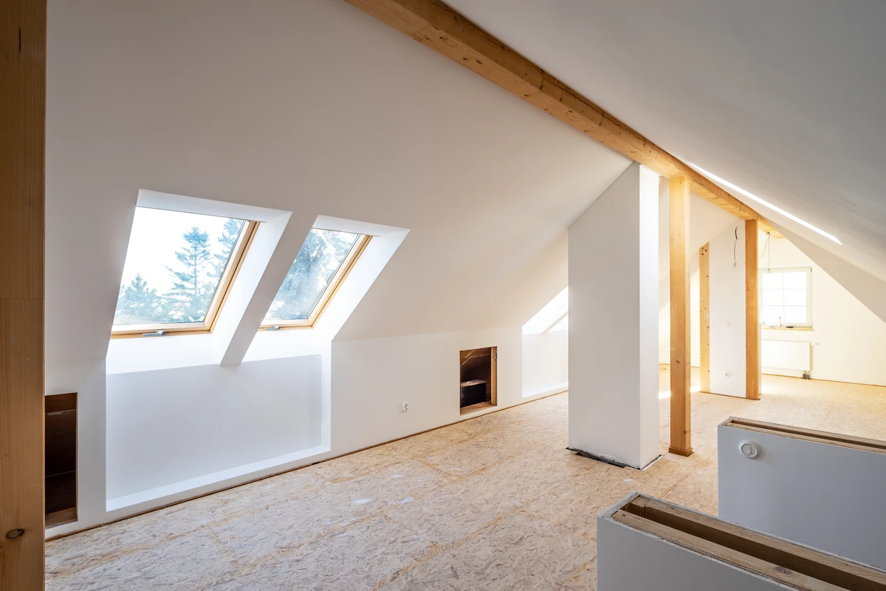 Combles aménagés en cours de finition avec charpente bois apparente et cloisons blanches