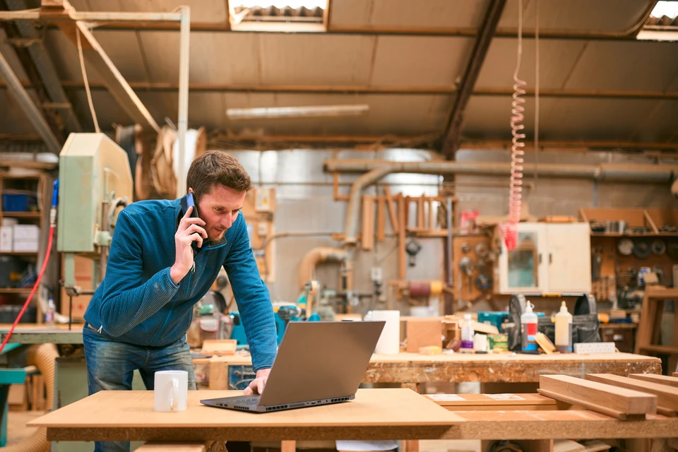Gros plan sur des mains d'artisans avec des gants mesurant une planche en bois avec une règle et un crayon